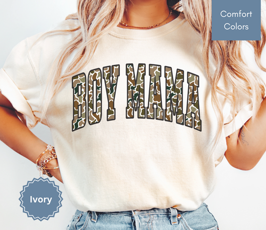 Woman wearing an ivory shirt with camouflage "BOY MAMA" text design.