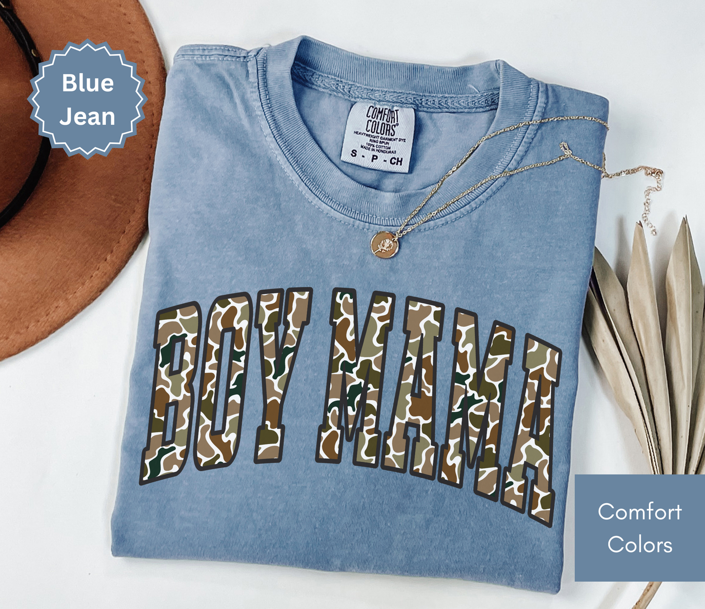 Folded blue jean color shirt with camouflage "BOY MAMA" text design.