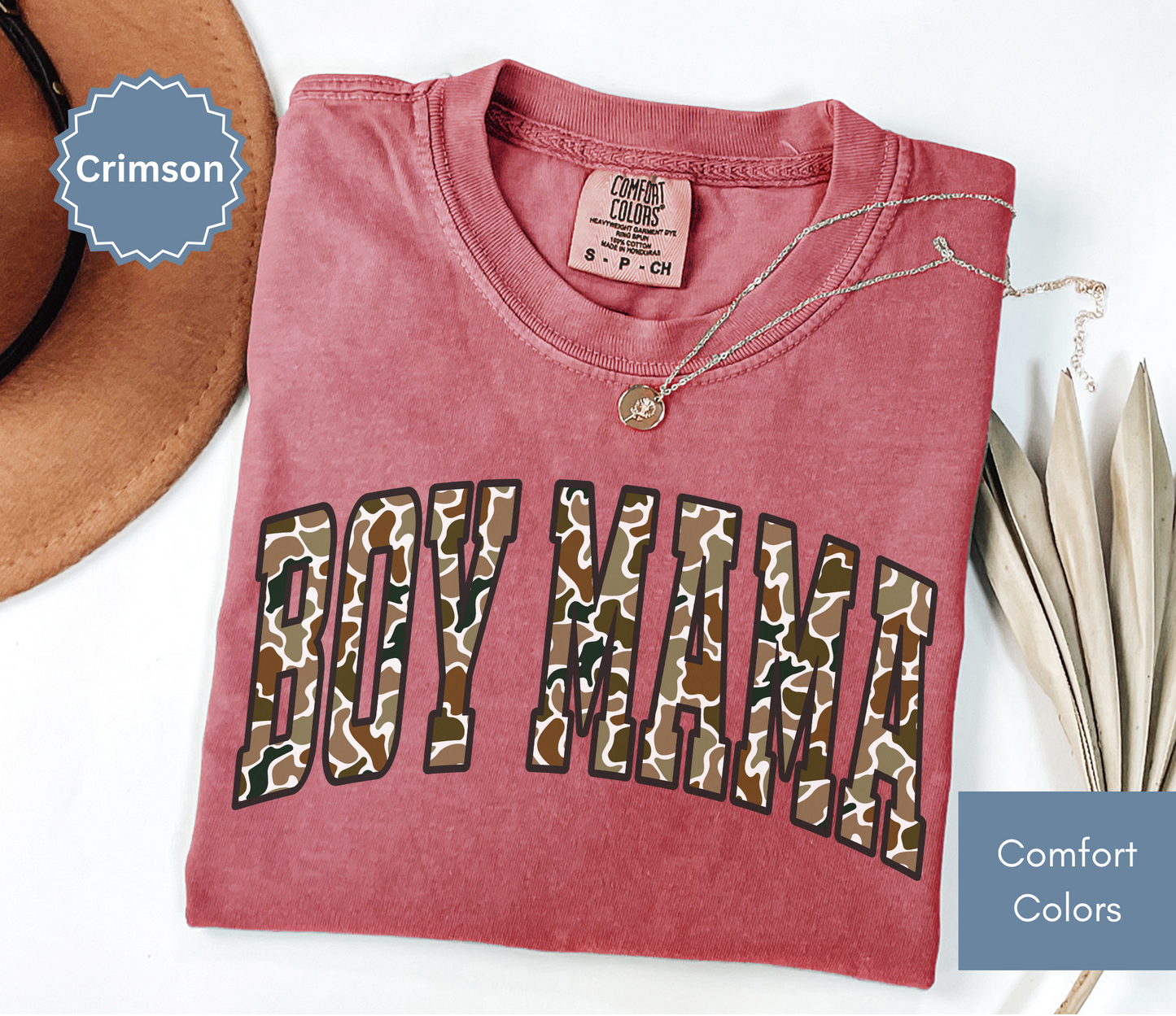 Folded crimson red shirt with camouflage "BOY MAMA" text design.