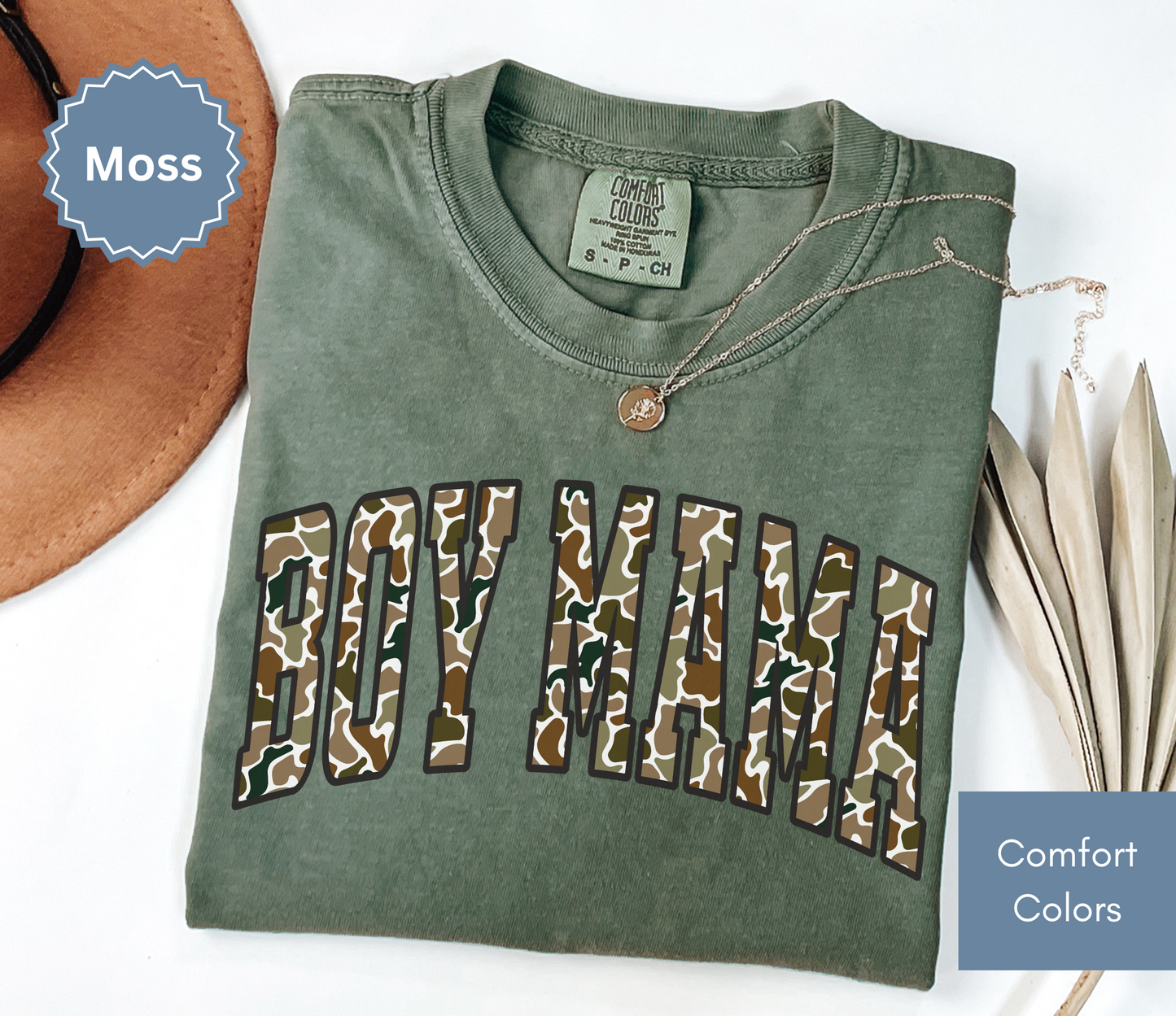 Folded moss green shirt with camouflage "BOY MAMA" text design.