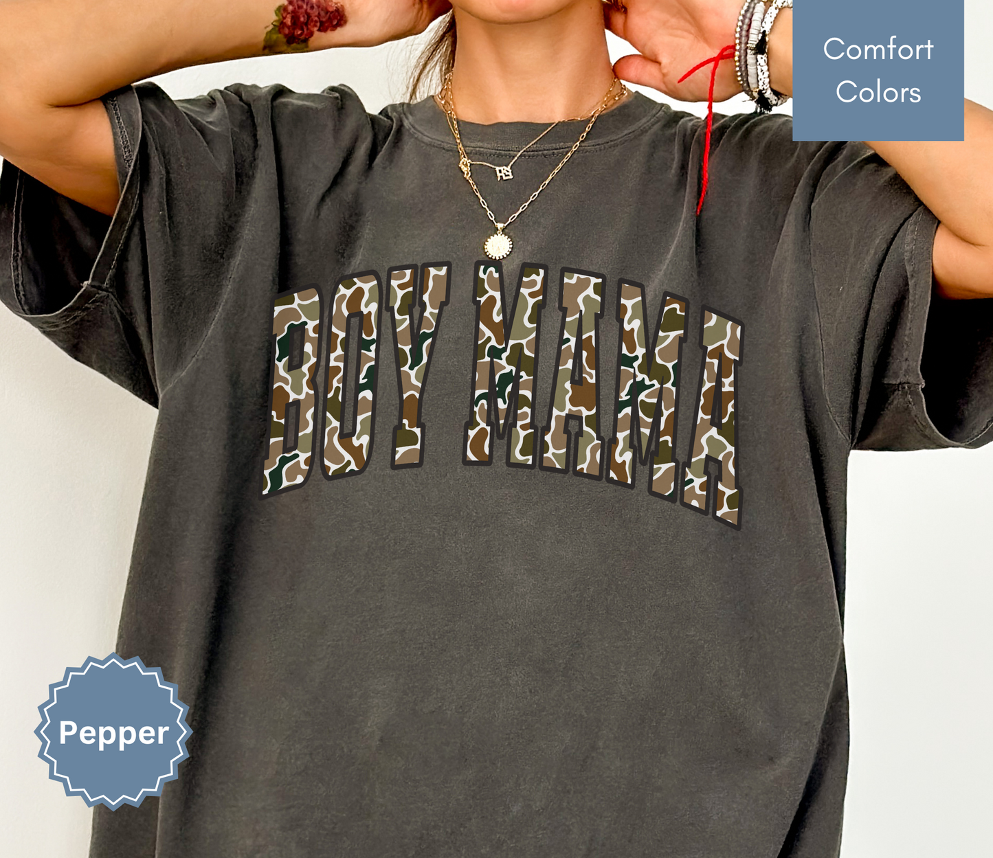 Woman wearing a dark grey shirt with camouflage "BOY MAMA" text design.