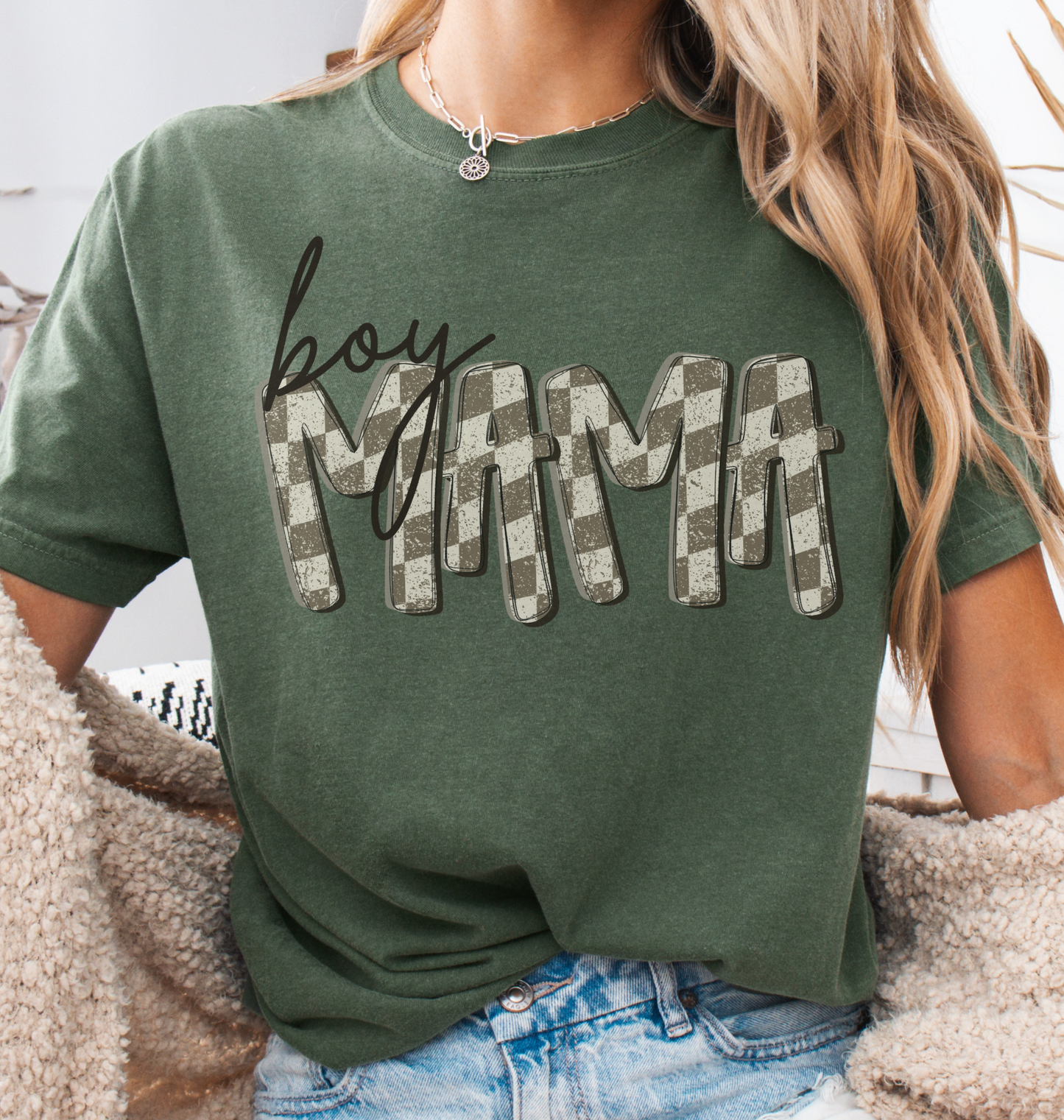 Woman wearing a moss green comfort colors t-shirt with retro checkered 'BOY MAMA' text.