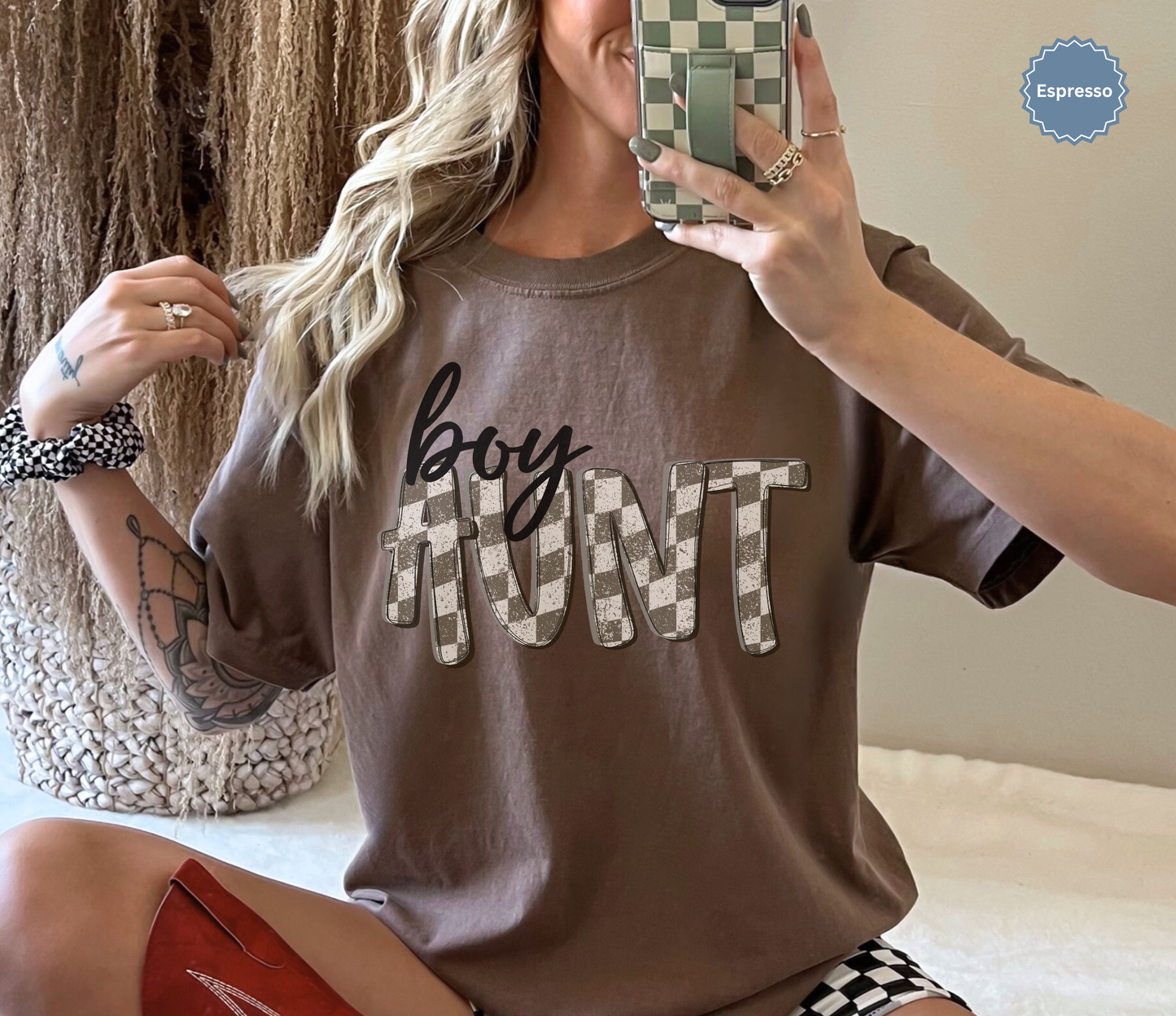 Woman wearing an espresso brown comfort colors t-shirt with retro checkered 'boy aunt' text.