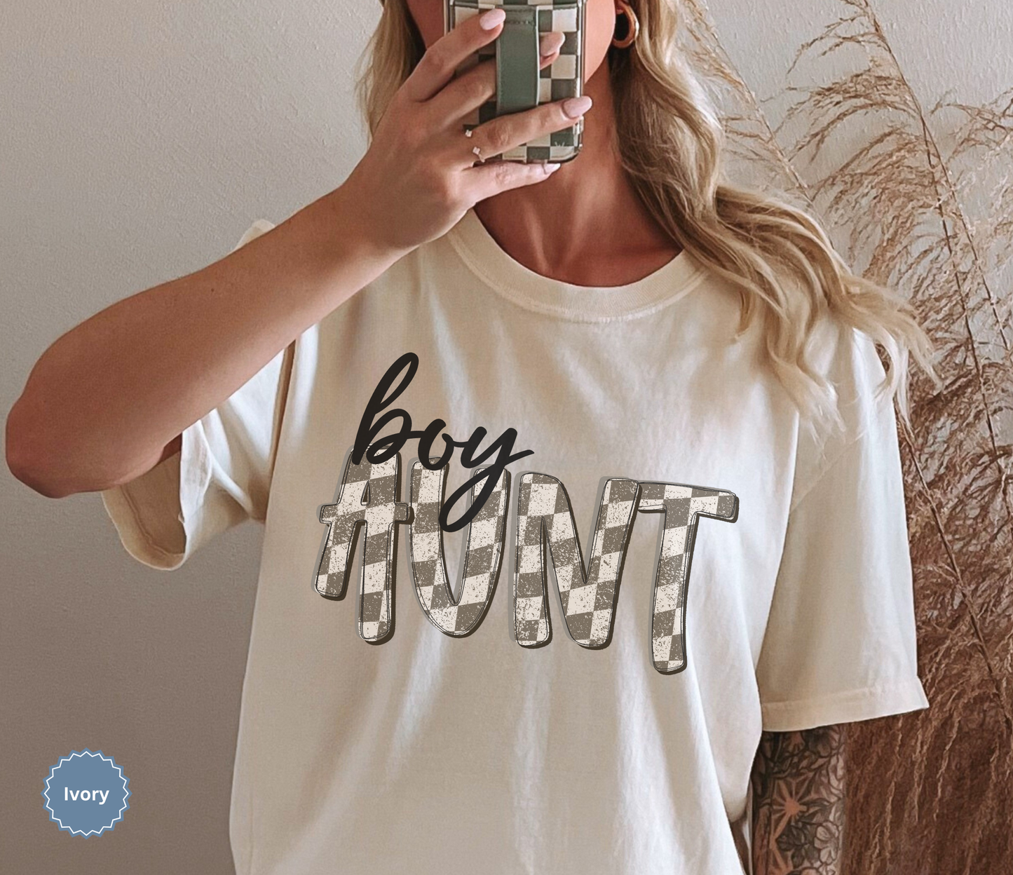 Woman wearing an ivory comfort colors t-shirt with retro checkered 'boy aunt' text.