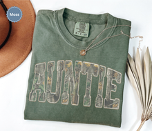 Load image into Gallery viewer, Folded comfort colors moss green t-shirt with 'AUNTIE' printed in distressed camo.
