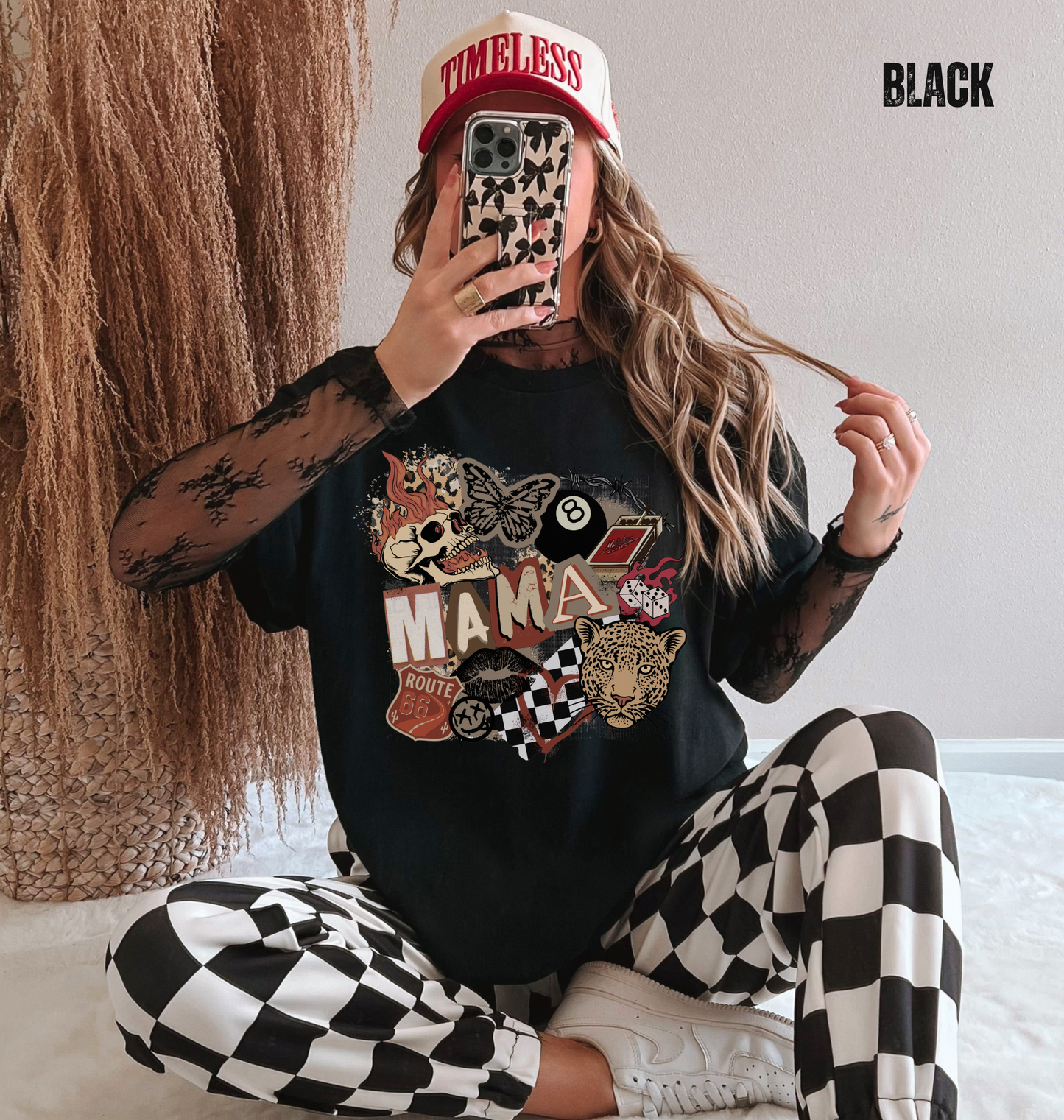Woman wearing a black comfort colors t-shirt with a western style graphic 'MAMA' design with a skull, leopard and checkered patterns.