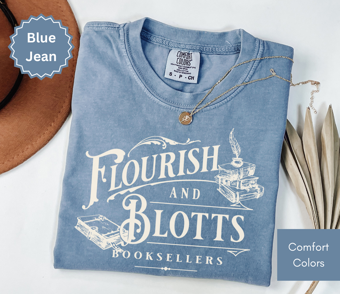 Folded blue jean colored comfort colors t-shirt with 'Flourish and Blotts Booksellers' design on a white background.