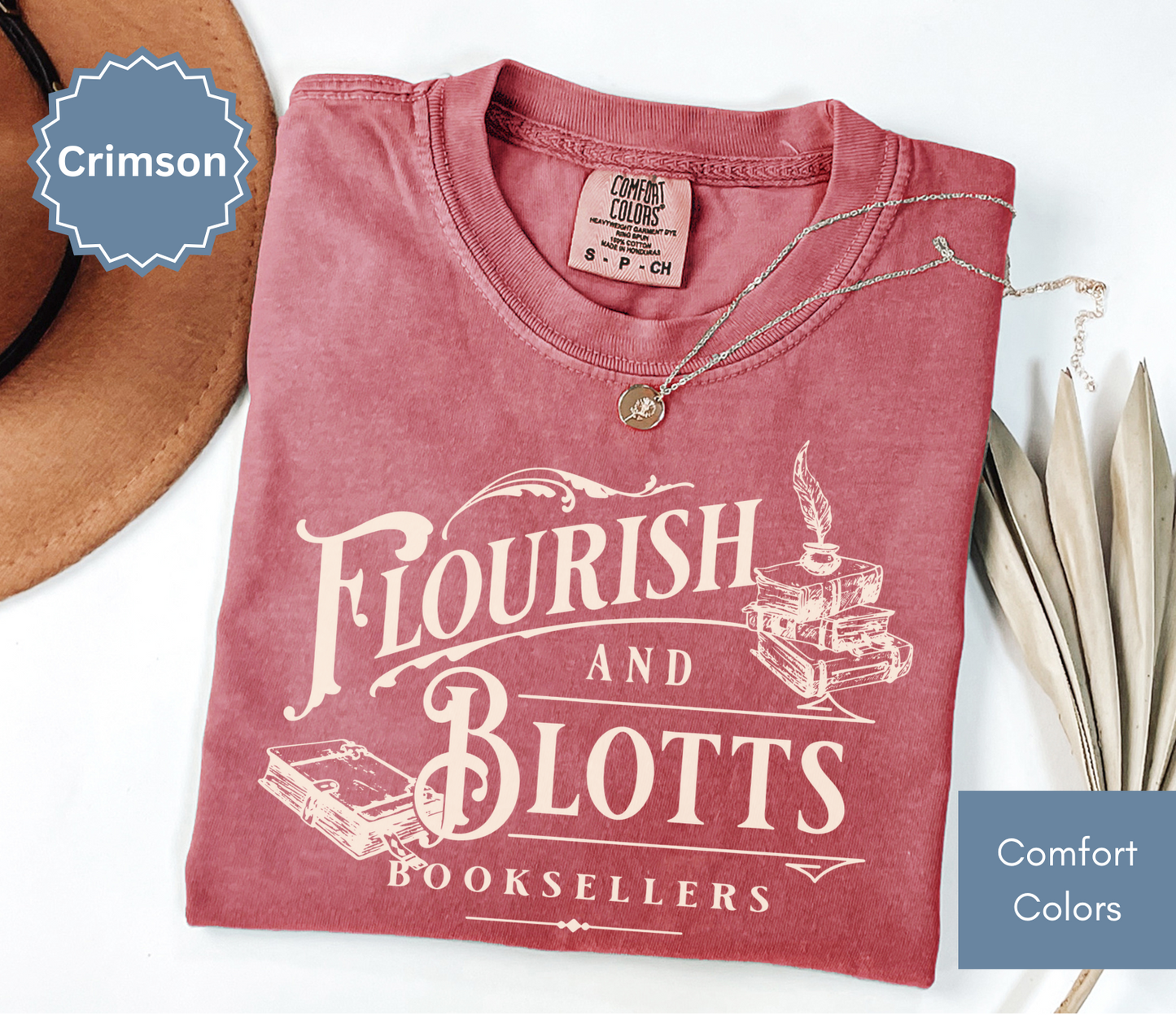 Folded crimson red comfort colors t-shirt with 'Flourish and Blotts Booksellers' design on a white background.