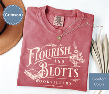 Load image into Gallery viewer, Folded crimson red comfort colors t-shirt with 'Flourish and Blotts Booksellers' design on a white background.
