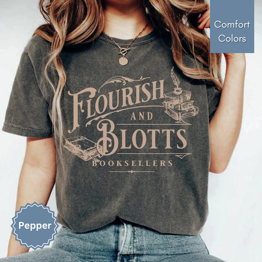 Woman wearing a dark grey pepper comfort colors t-shirt with 'Flourish and Blotts Booksellers' design on a white background.