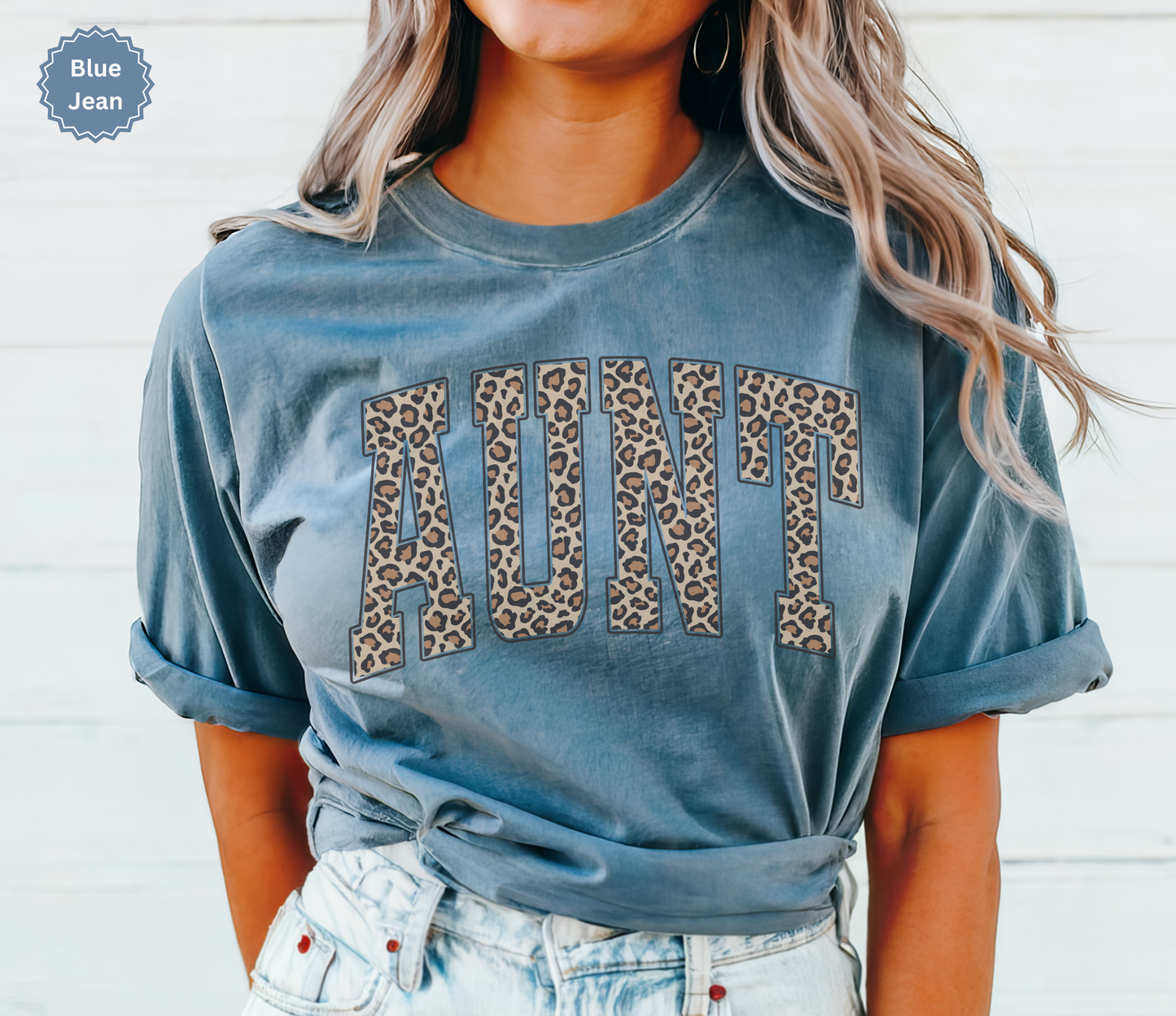 Woman wearing a blue jean colored Comfort Colors t-shirt with leopard print 'AUNT' varsity text.