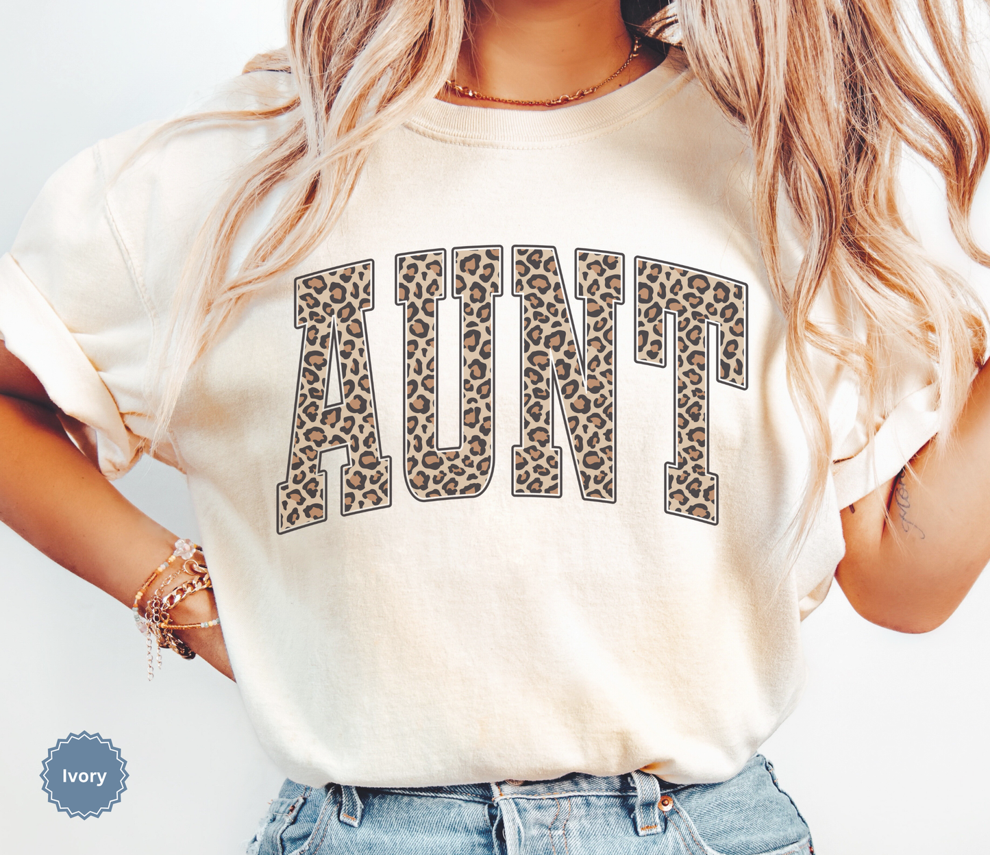 Woman wearing an ivory Comfort Colors t-shirt with leopard print 'AUNT' varsity text.