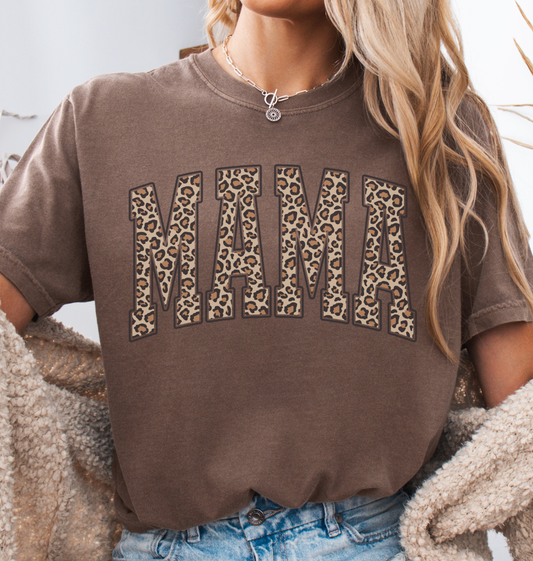 Woman wearing an espresso brown comfort colors t-shirt with 'MAMA' in leopard print.