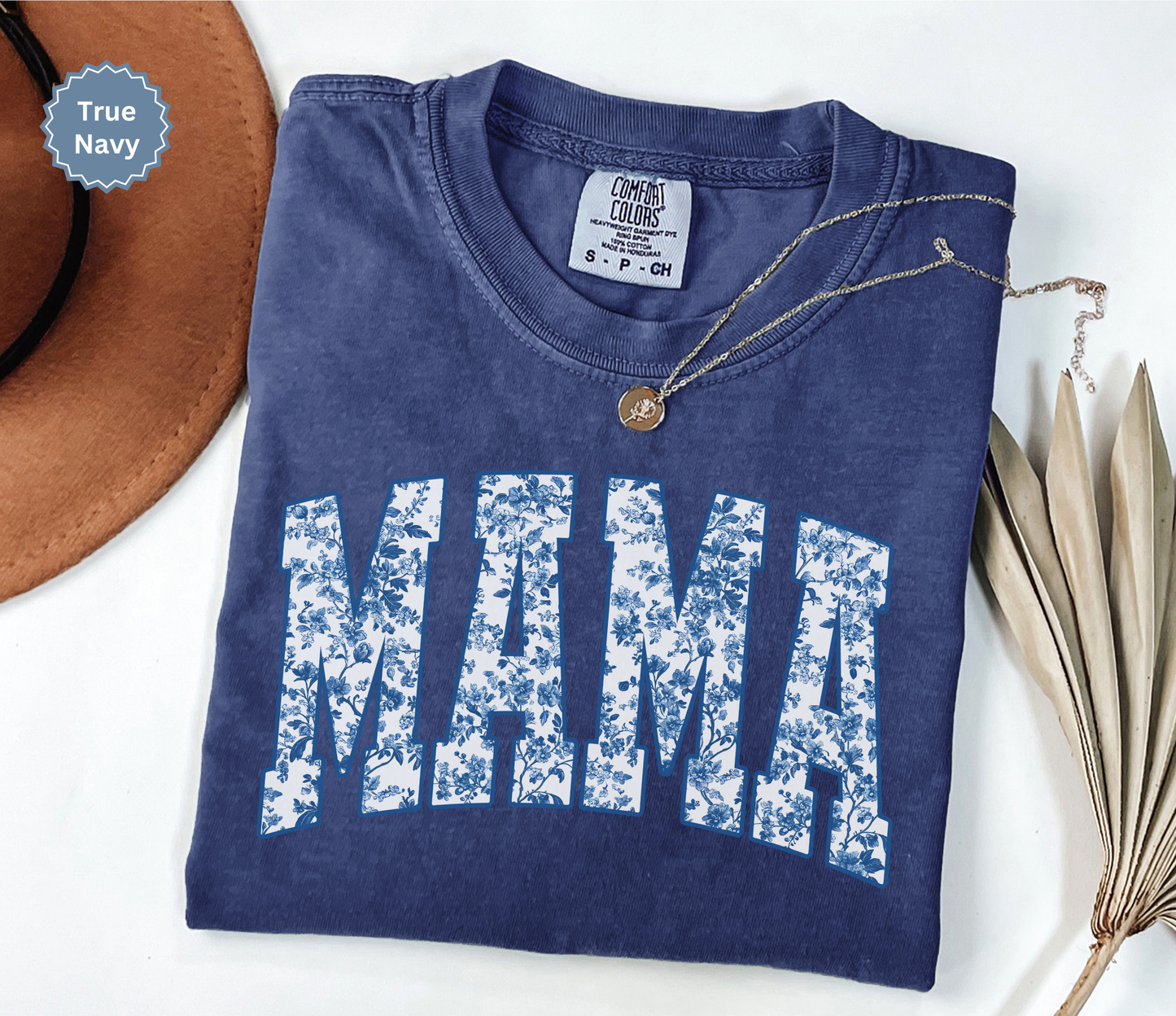 Folded navy blue t-shirt with 'MAMA' toile floral print design.