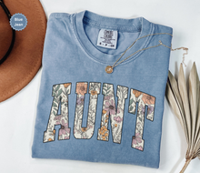 Load image into Gallery viewer, Comfort colors blue jean colored t-shirt with floral 'AUNT' varsity text
