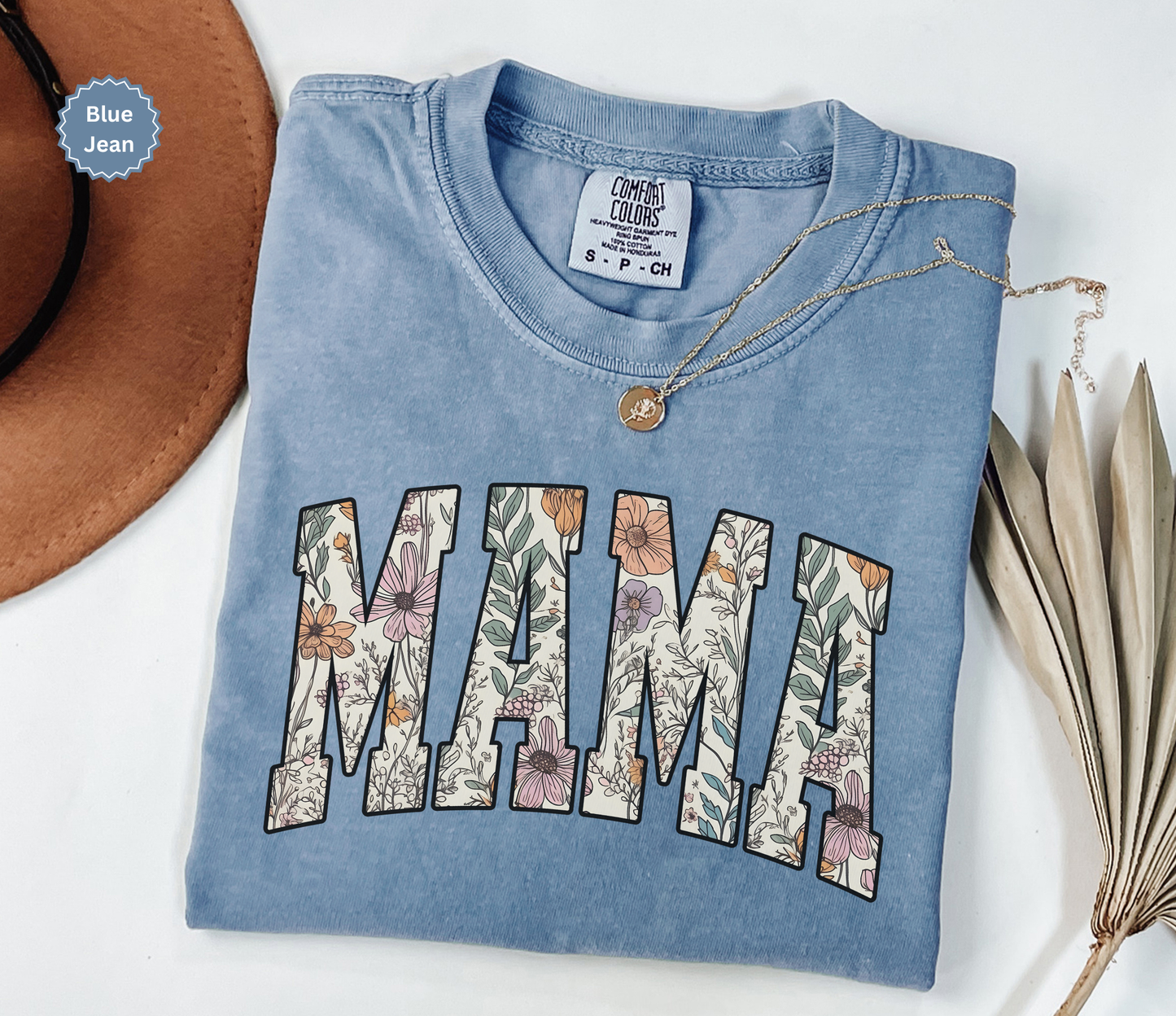 Folded blue jean color T-shirt with a varsity style "MAMA" floral print. 
