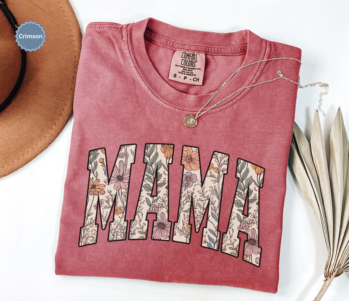 Folded crimson red T-shirt with a varsity style "MAMA" floral print. 