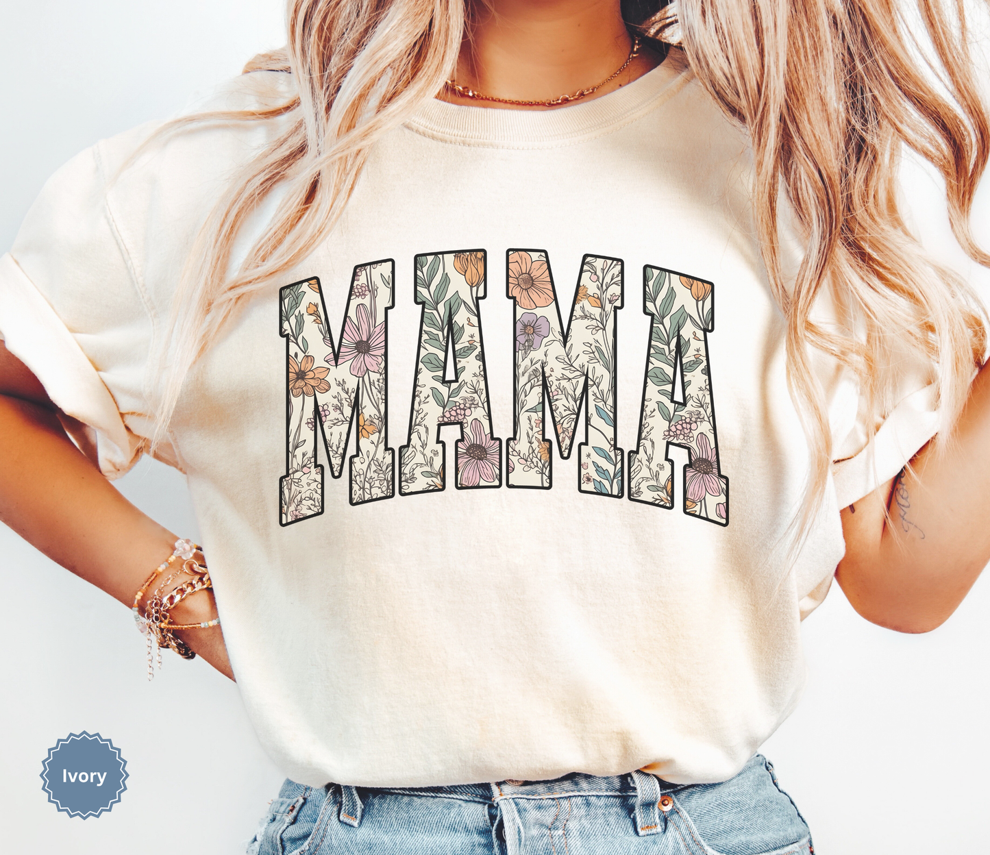 Woman wearing an Ivory T-shirt with a varsity style "MAMA" floral print. 